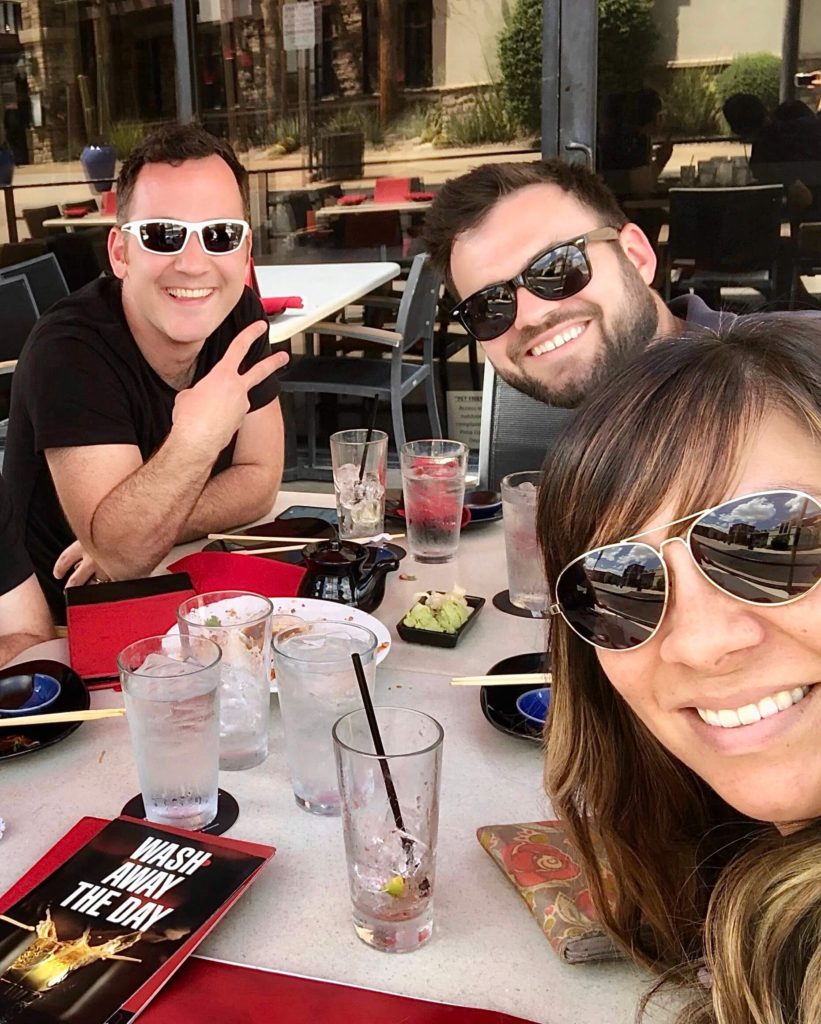 3 people at a table all wearing sunglasses taking an usie