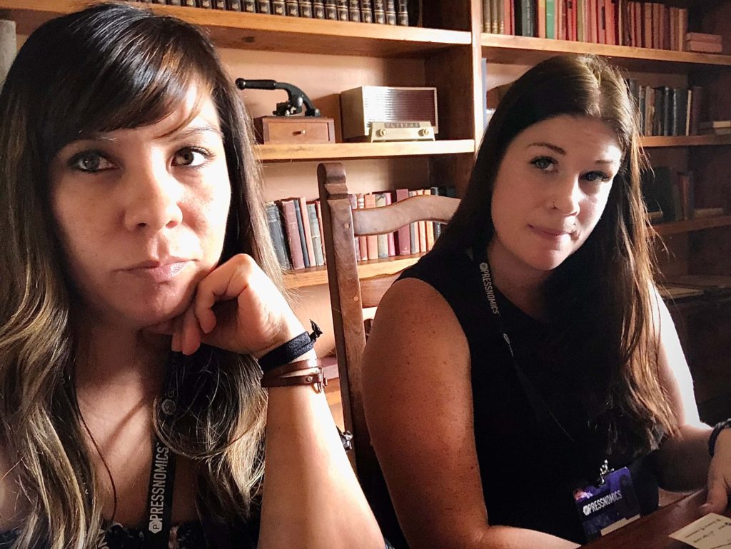 two women sitting taking an usie in front of a book shelf