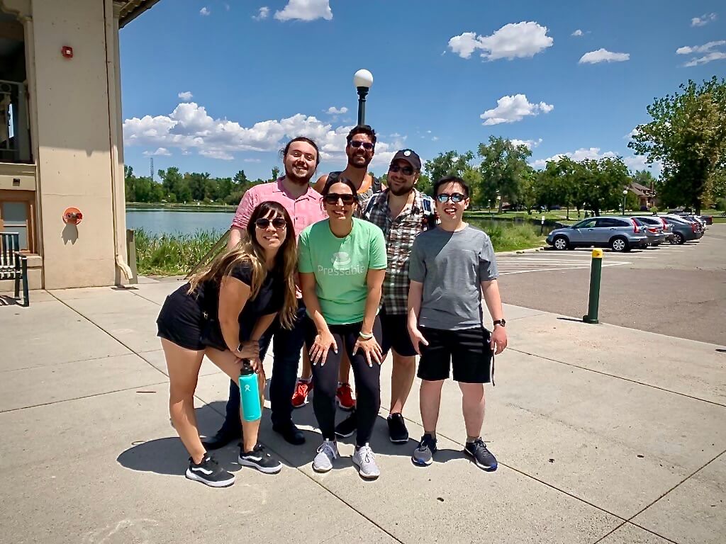 people taking a group pic in front of a lake at a park